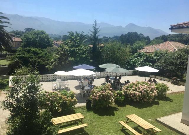 a garden with picnic tables and umbrellas and chairs at Albergue Internacional de Llanes in Llanes