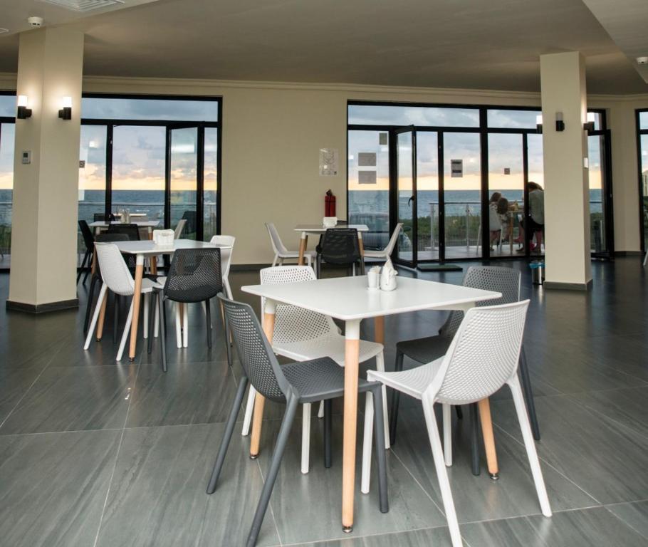 a dining room with tables and chairs and windows at Hotel Scala in Shekhvetili