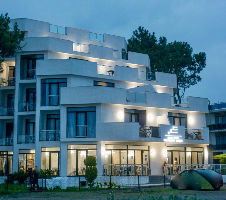 谢赫维蒂利Hotel Scala的一座白色的大建筑,前面有人站在