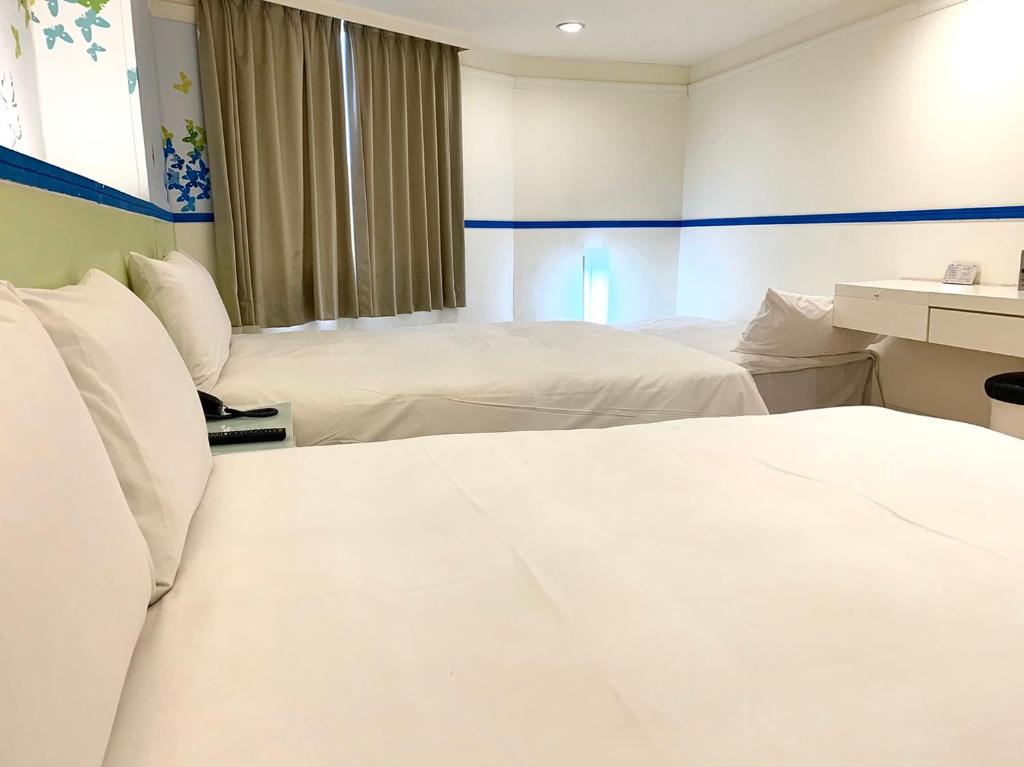 two beds in a hotel room with white sheets at Kiwi Express Hotel - Zhong Zheng Branch in Taichung