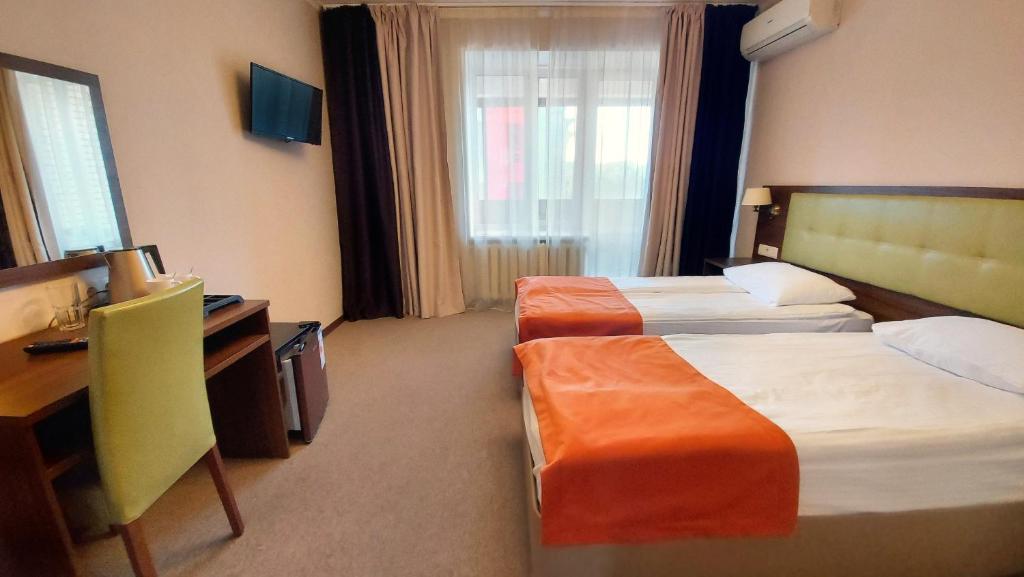 モスクワにあるDom Veteranov Kinoのベッド2台とデスクが備わるホテルルームです。