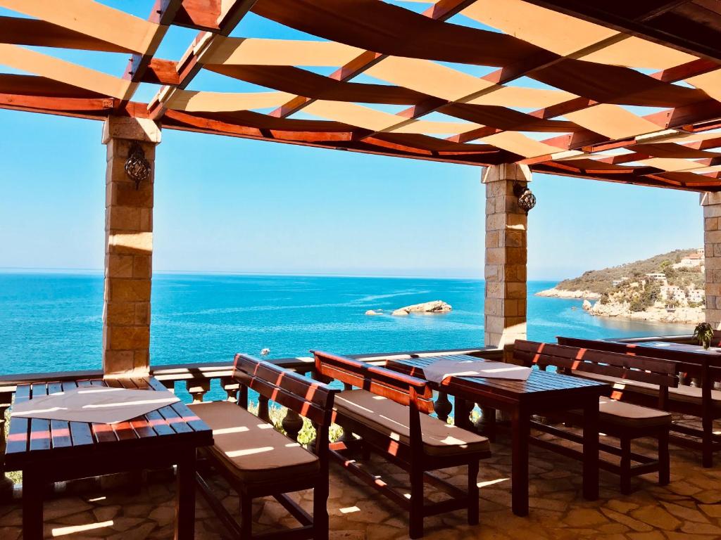 a patio with tables and chairs and a view of the ocean at Guest house Naser in Ulcinj