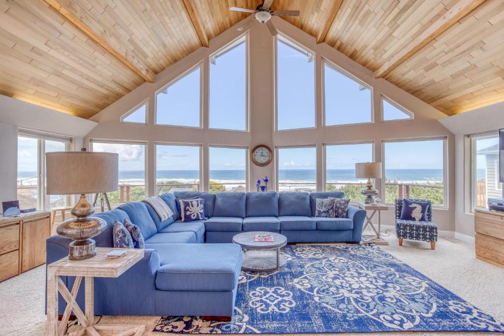 a living room with a blue couch and windows at Neptune Lookout in Lincoln City