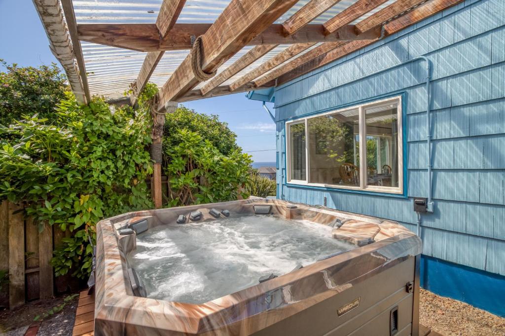 uma banheira de hidromassagem no quintal de uma casa azul em Sea Haven em Lincoln City