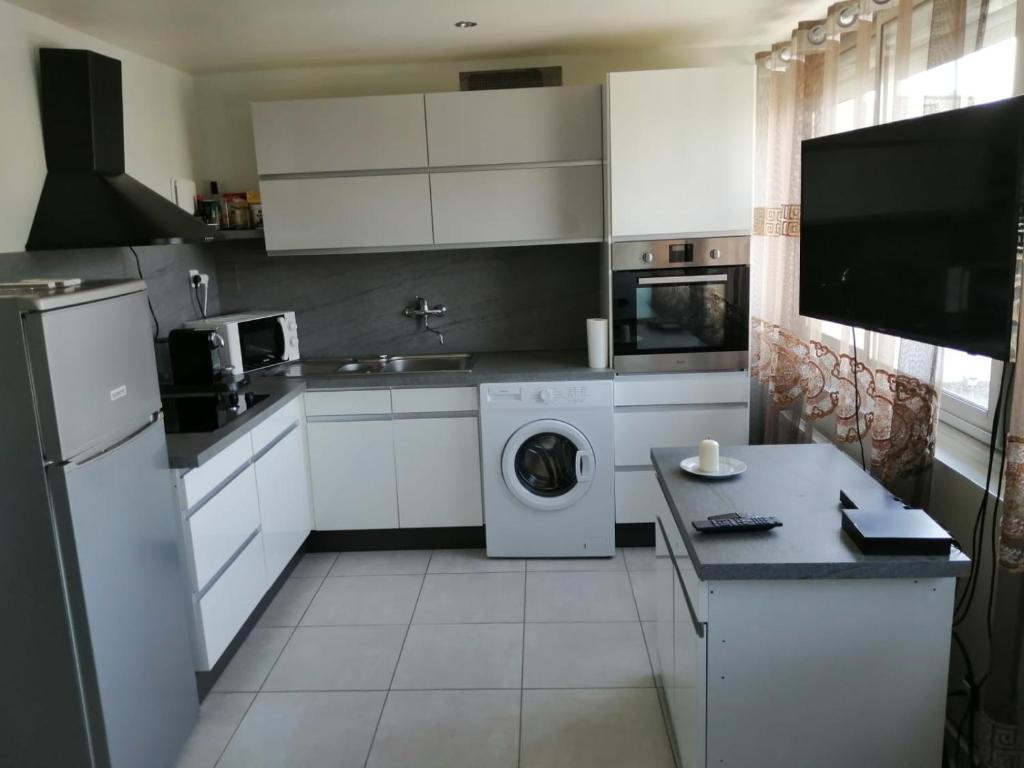 a kitchen with white cabinets and a washer and dryer at Location d'appartement entièrement meublé près de Genève in Annemasse
