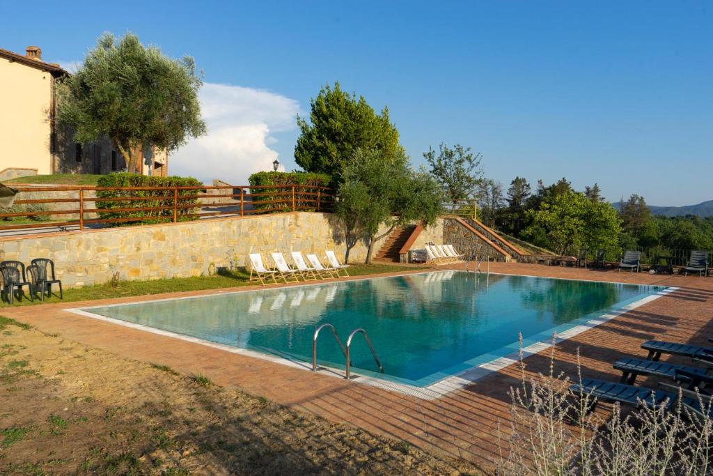 a swimming pool in a yard with chairs around it at Tenuta Toscanità in Cavriglia