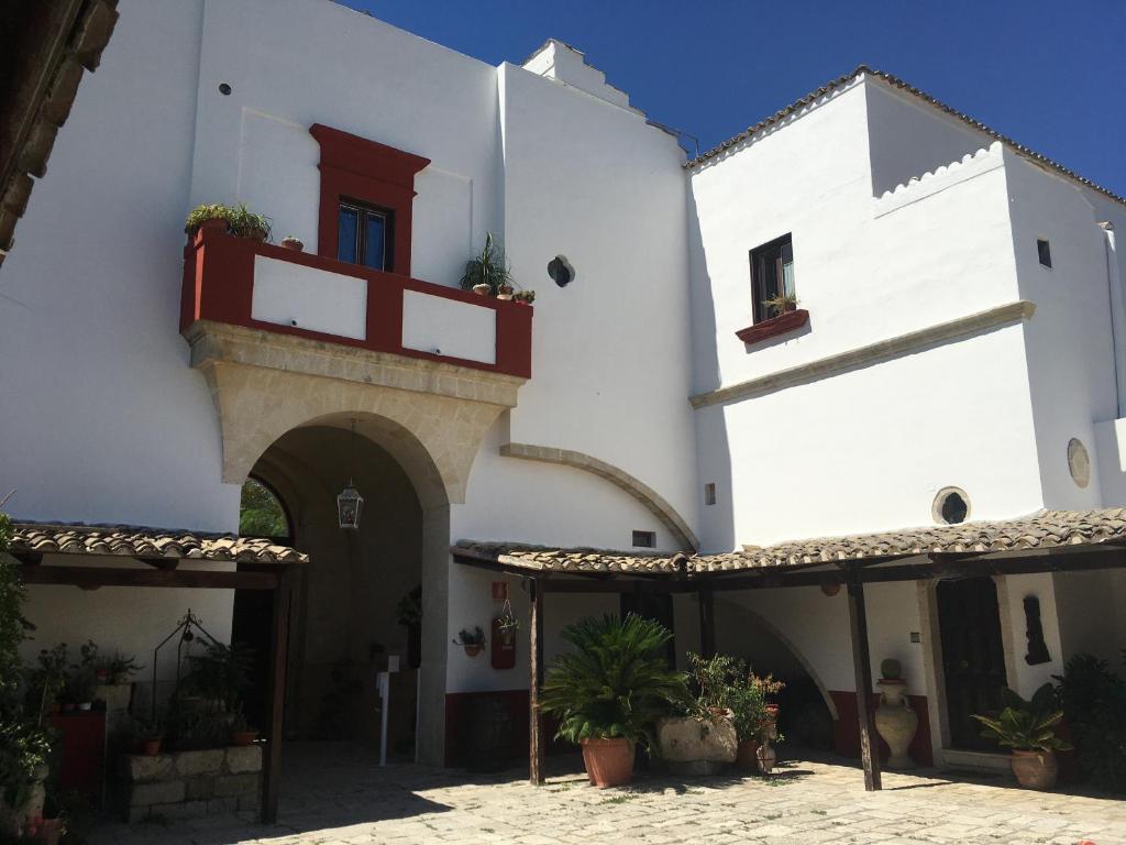 a white building with a red door and a balcony at Oasi Rupestre in Montescaglioso