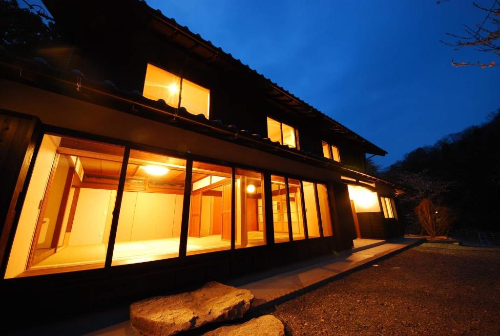 um edifício com janelas e uma pedra em frente em Cominka Hotel Shiki no Ie - Vacation STAY 89847 em Mitake
