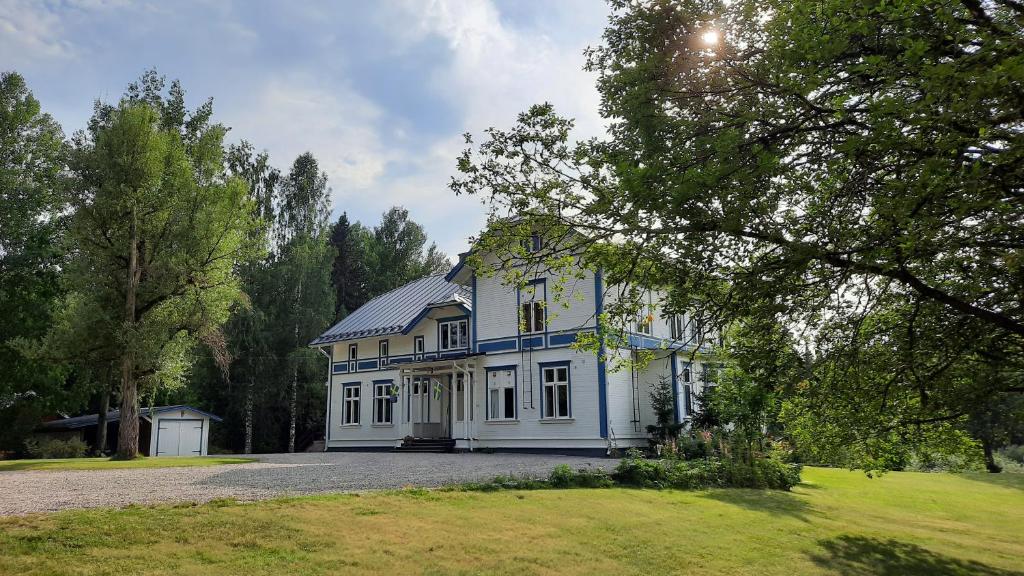 a large blue and white house with a yard at Geijersholms Herrgård in Hagfors