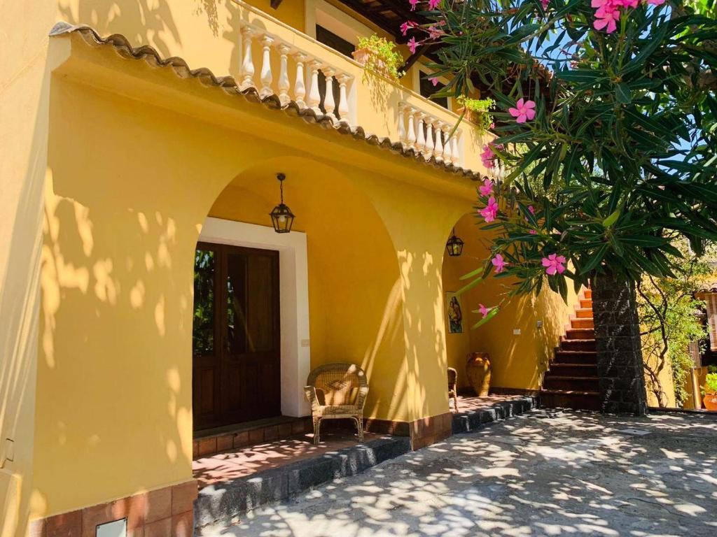 Villa Le Gemelle Dell'Alcantara في Motta Camastra: منزل أصفر مع درج يؤدي إلى الباب الأمامي