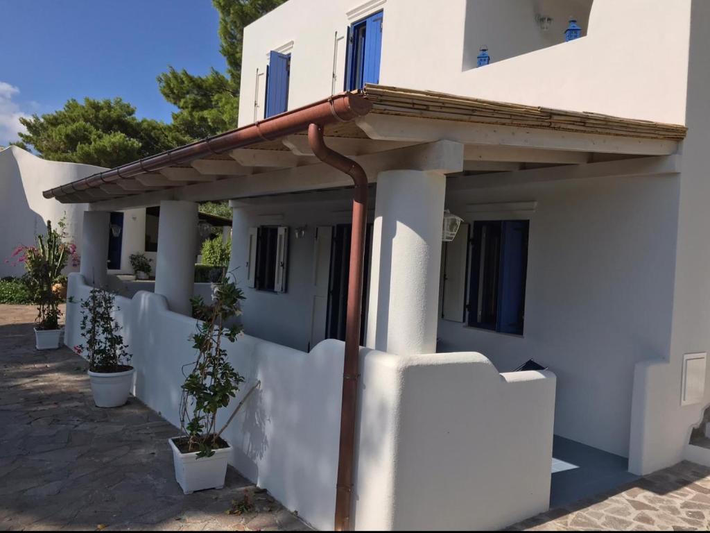 una casa bianca con recinzione e piante in vaso di Le Dimore della Villa dei Sogni a Vulcano