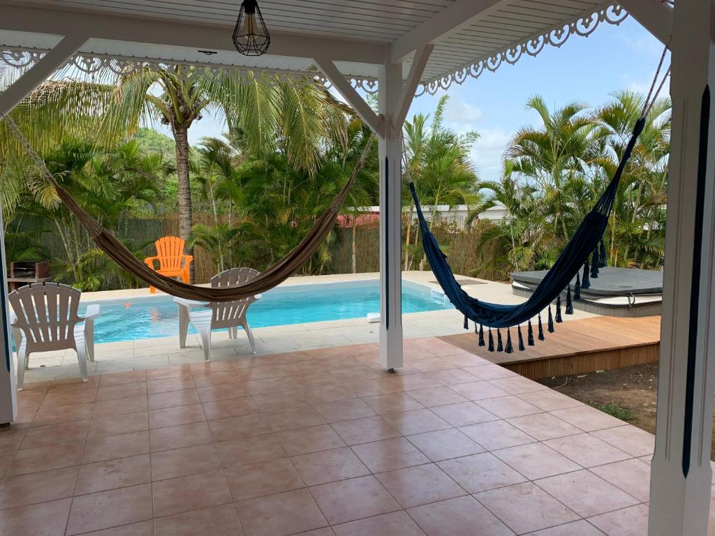 a patio with two hammocks and a pool at Villa Bois d'Inde in Le Diamant