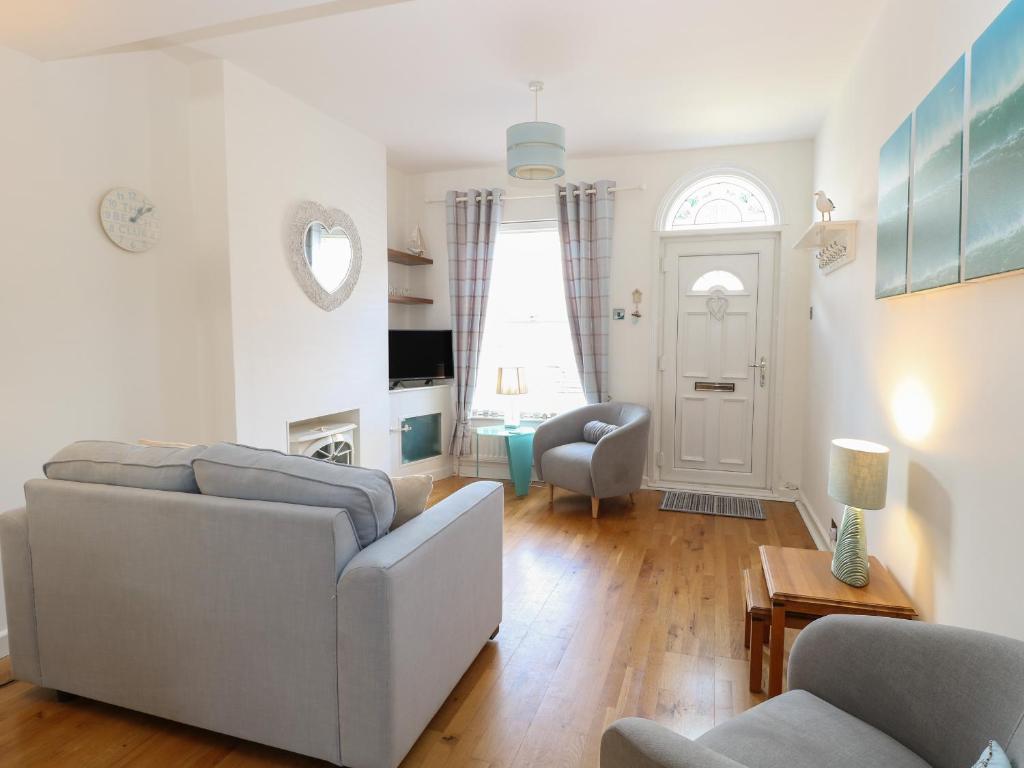 ein Wohnzimmer mit einem Sofa und einem Stuhl in der Unterkunft Gull's Nest in Lowestoft