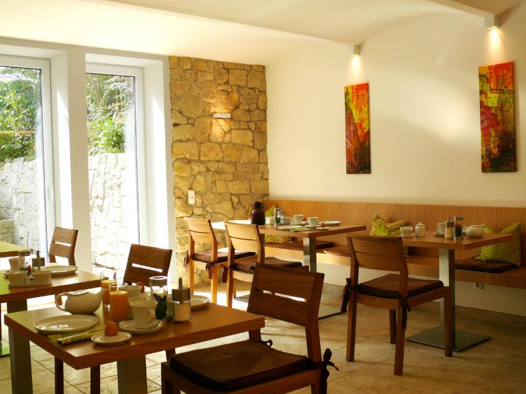 a restaurant with wooden tables and chairs and a stone wall at Villa Am Park in Erfurt