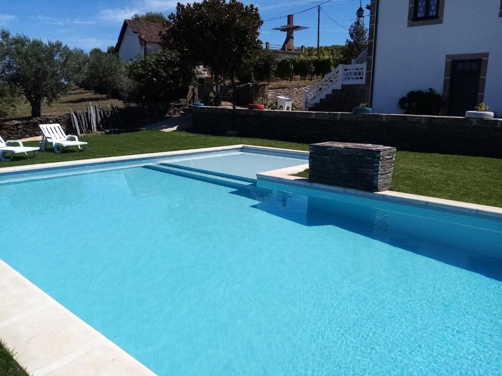 a large blue swimming pool in front of a house at Solar dos Avós in Sabrosa