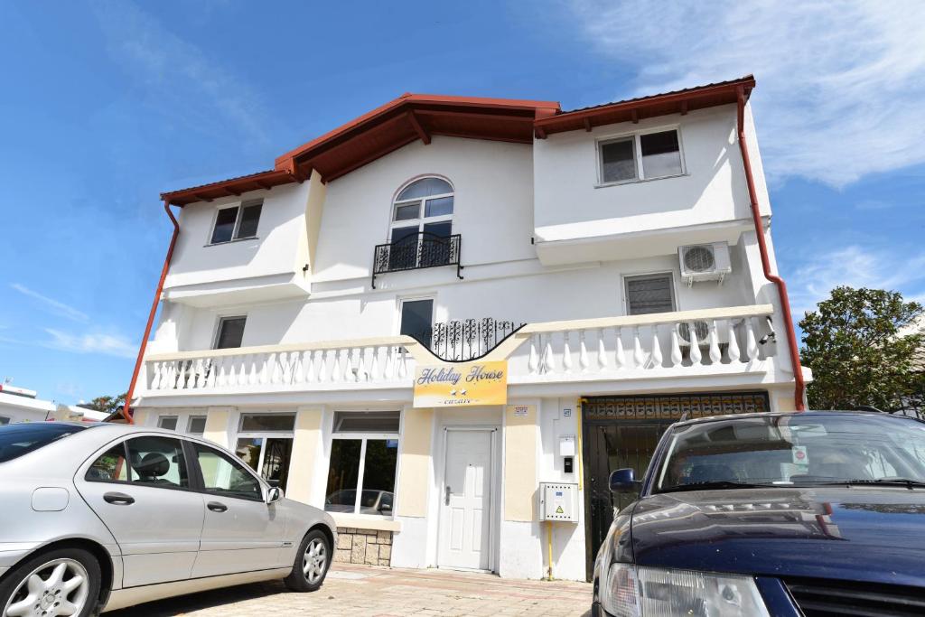 a white building with cars parked in front of it at Holiday House Costinesti in Costinesti