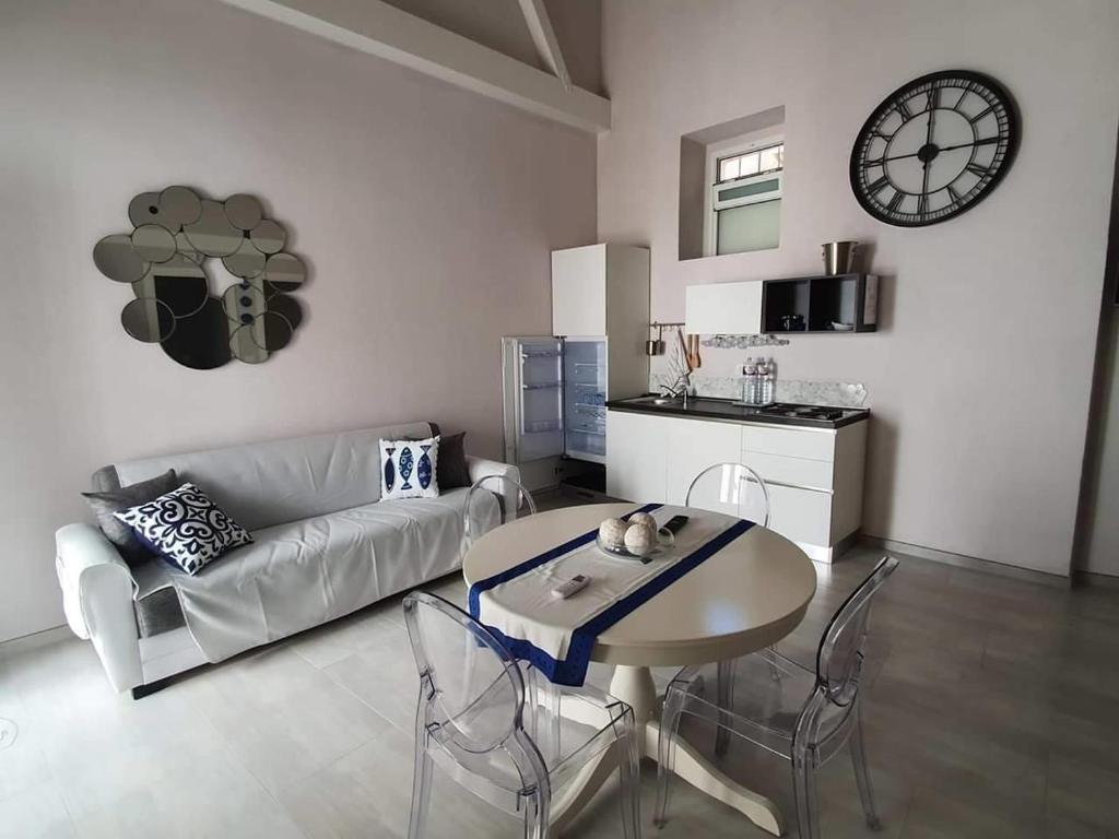 ein Wohnzimmer mit einem Sofa, einem Tisch und einer Uhr in der Unterkunft Casa Bolle Ortigia in Syrakus