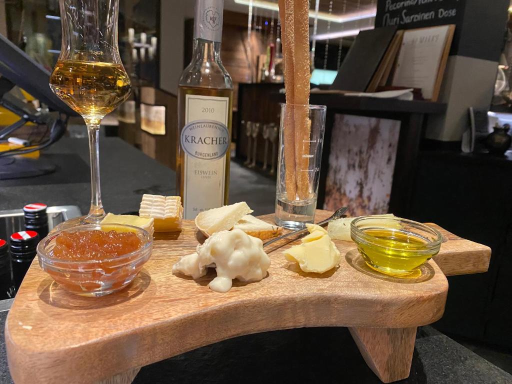 a wooden cutting board with cheese and a bottle of wine at Hotel Central in Gerlos