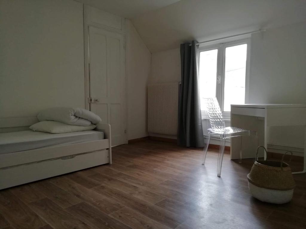 una camera con un letto e una sedia e una finestra di Maison à deux pas de la mer a Wimereux