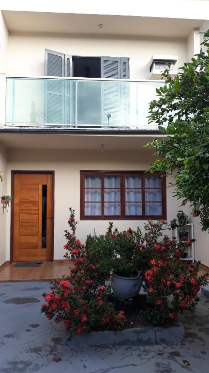 a house with a balcony and flowers in front of it at Casa Tapajos in Ubatuba