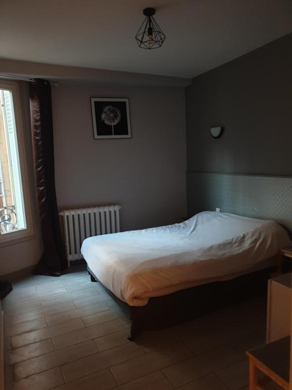 a bedroom with a bed in a room with a window at Hôtel Belfort in Montreuil