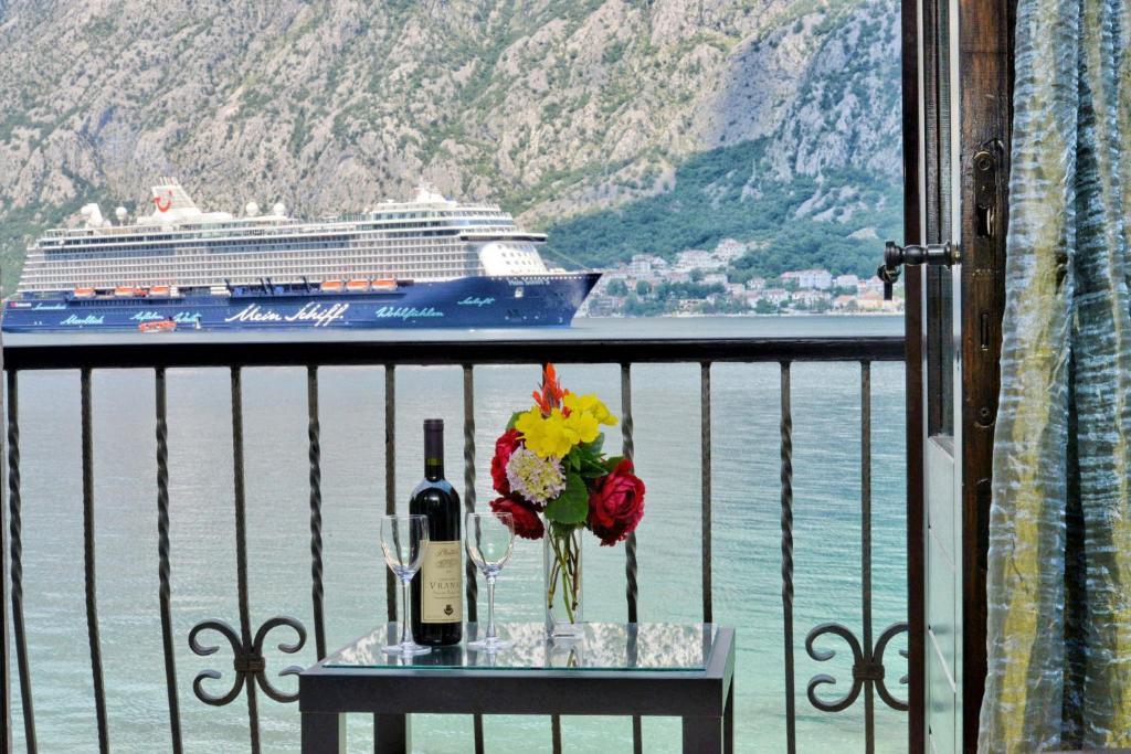 a table with a bottle of wine and a cruise ship at Apartments Saxo in Kotor