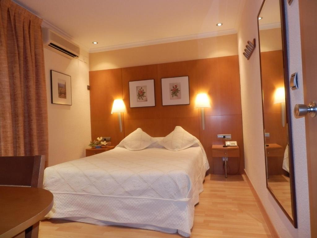 Habitación de hotel con cama blanca y espejo en Hotel Restaurante Salvadora, en Villena
