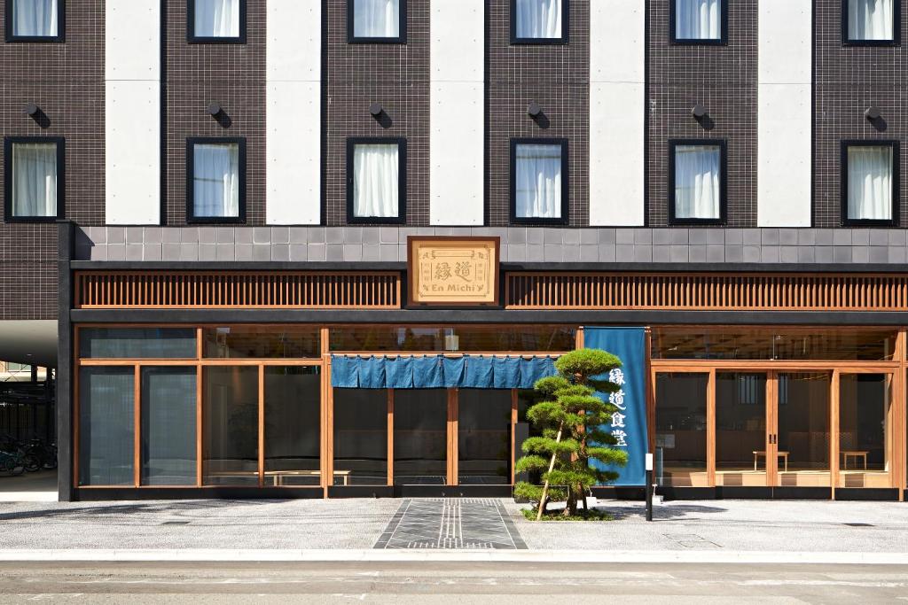 un edificio con un árbol delante en HOTEL Enmichi, en Kawasaki