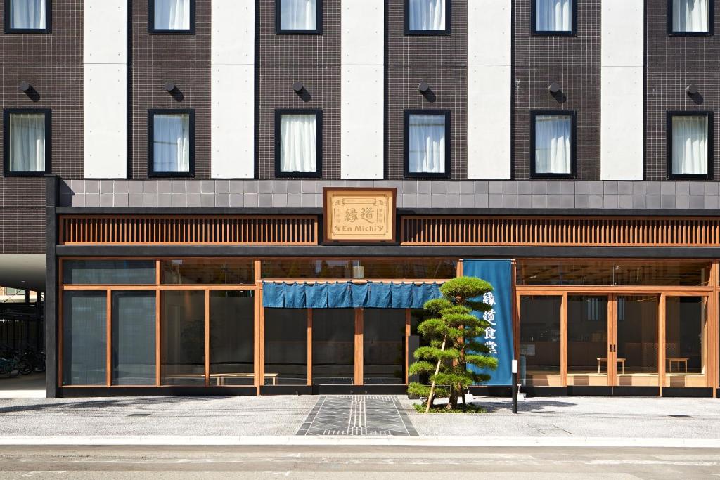 un bâtiment avec un arbre en face dans l'établissement HOTEL Enmichi, à Kawasaki