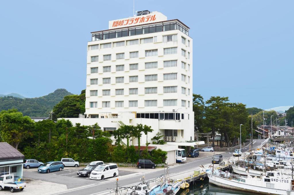 un edificio de hotel con coches aparcados frente a un puerto deportivo en Oki Plaza Hotel, en Okinoshima