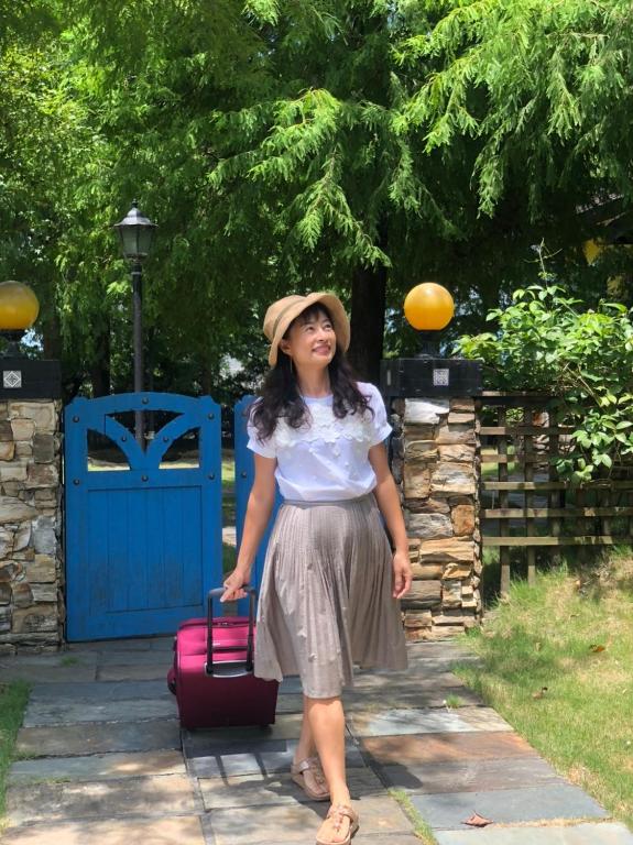 a woman wearing a hat and holding a suitcase at Rothenburg Lodge in Wujie