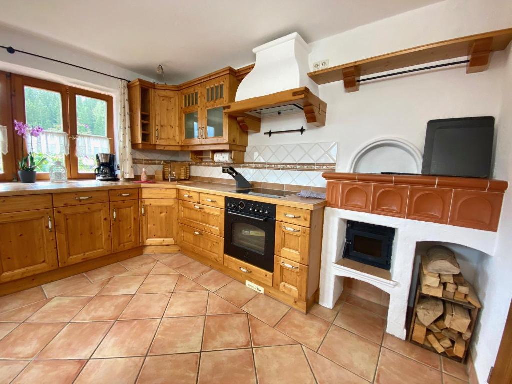 a large kitchen with wooden cabinets and a fireplace at Ferienwohnung Vorberg in Schönau am Königssee