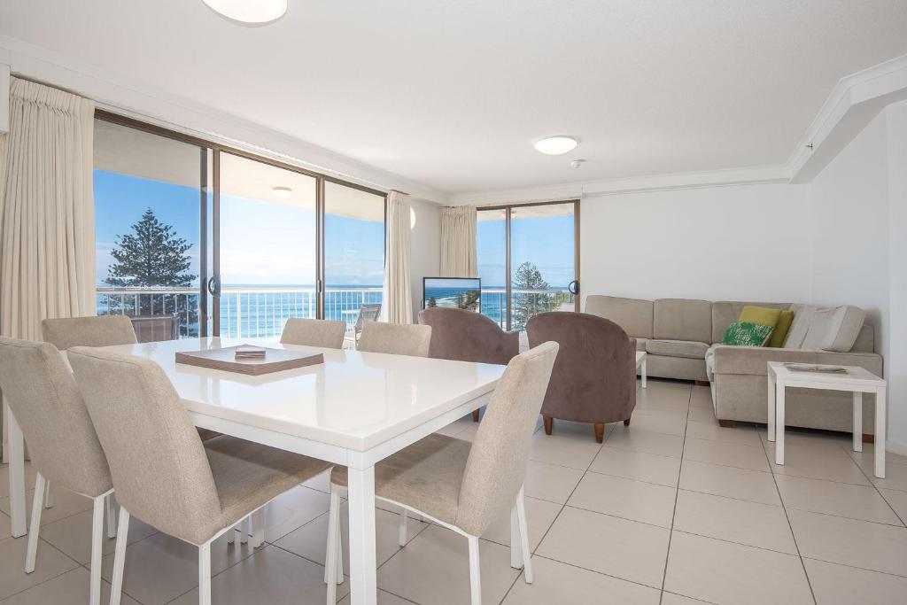a dining room with a white table and chairs at Coolum Caprice in Coolum Beach