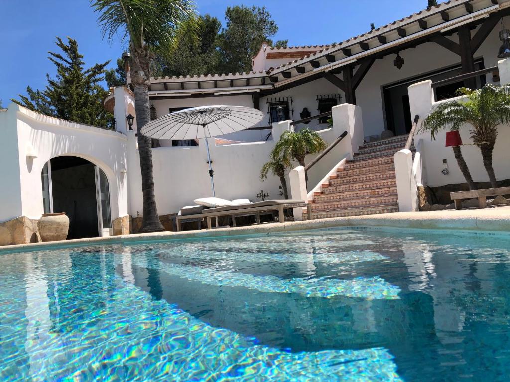 a swimming pool in front of a house with an umbrella at Villa Finca Costa Blanca Apartment 1 / Ferienwohnung 1; Monte Pego bei Denia in Monte Pego