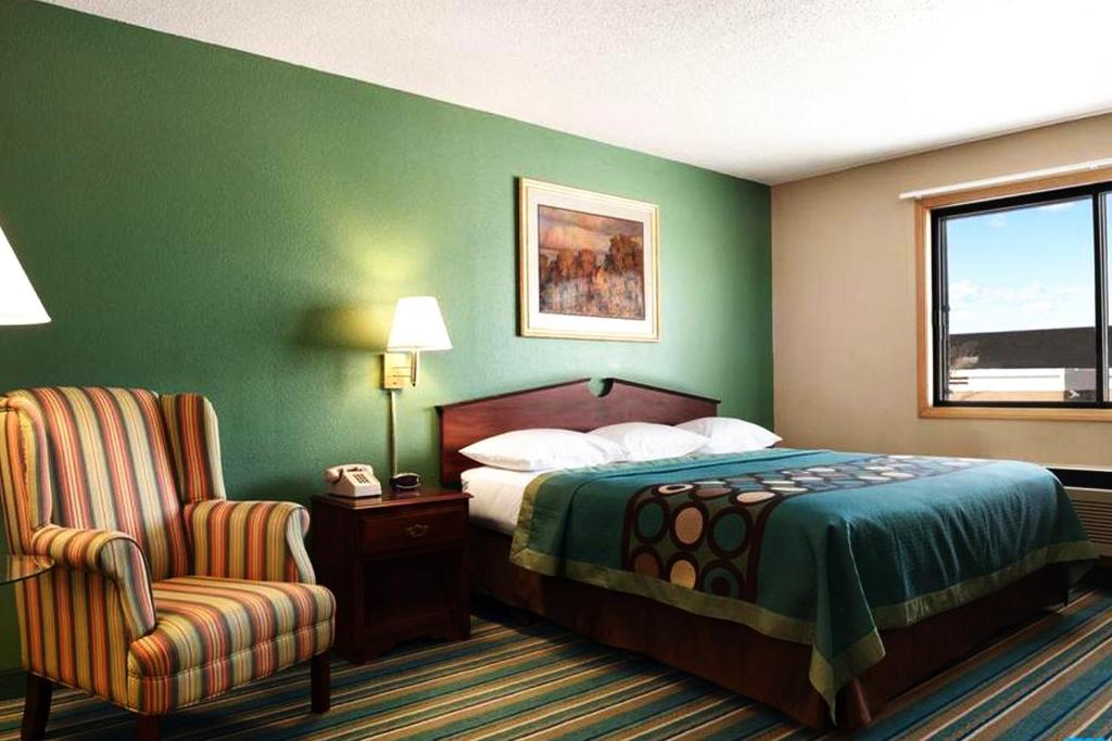 um quarto de hotel com uma cama e uma cadeira em Coratel Inn & Suites by Jasper New Richmond em New Richmond