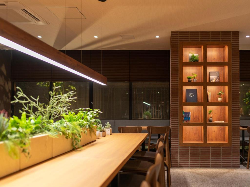 a dining room with a long table and some plants at Super Hotel Premier Kanazawaeki Higashiguchi in Kanazawa