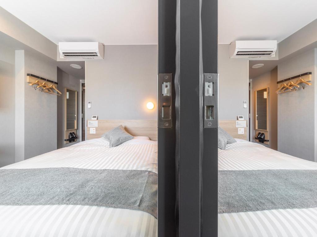 two beds in a bedroom with two mirrors at Super Hotel Premier Kanazawaeki Higashiguchi in Kanazawa