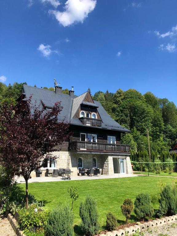 een groot huis op een groen gazon met bomen bij Willa Mała Czarna in Wisła