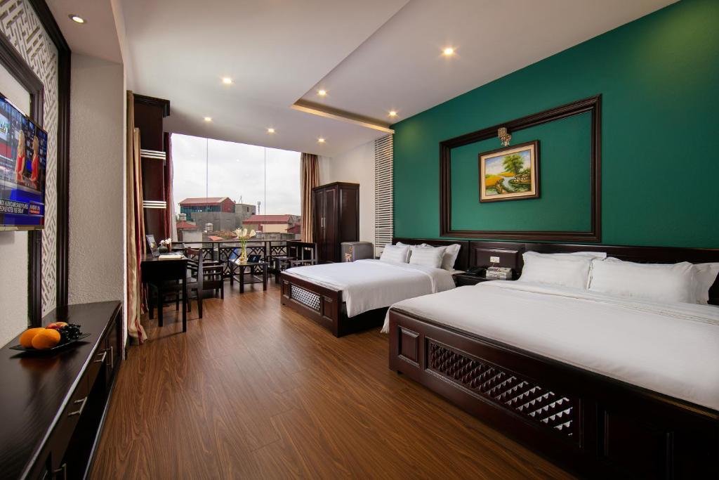ĐỨC TRỌNG HOTEL في هانوي: غرفة فندقية بسريرين وجدار أخضر