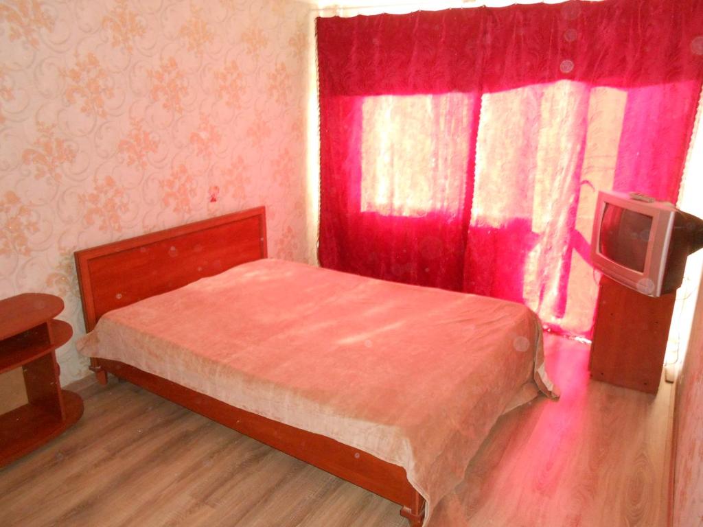 una camera con letto e finestra con tende rosse di Однокомнатная квартира рядом с метро Оболонь a Kiev