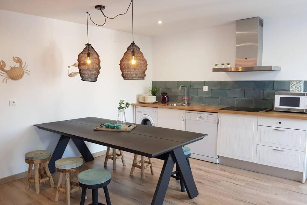 a kitchen with a table and stools in it at Amb encant i estil Mediterrani en zona tranquilla de Llançà i amb terrassa in Llança