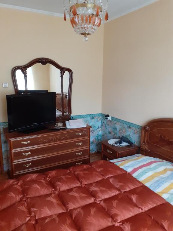 Schlafzimmer mit einem Bett und einer Kommode mit einem TV in der Unterkunft IOMAN HAUS in Ikšķile