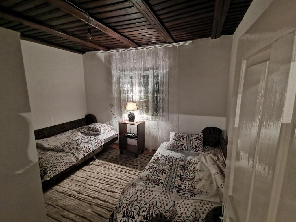 a bedroom with two beds and a table with a lamp at Konak Mileva in Sjenica