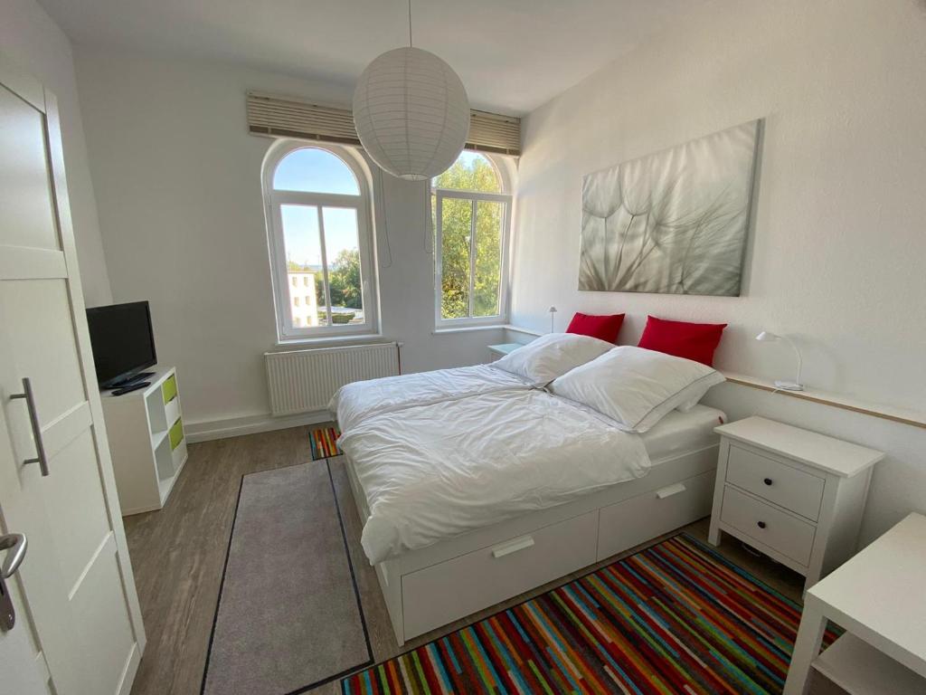 Schlafzimmer mit einem Bett mit weißer Bettwäsche und roten Kissen in der Unterkunft Apartments Rischmühle in Emmerthal