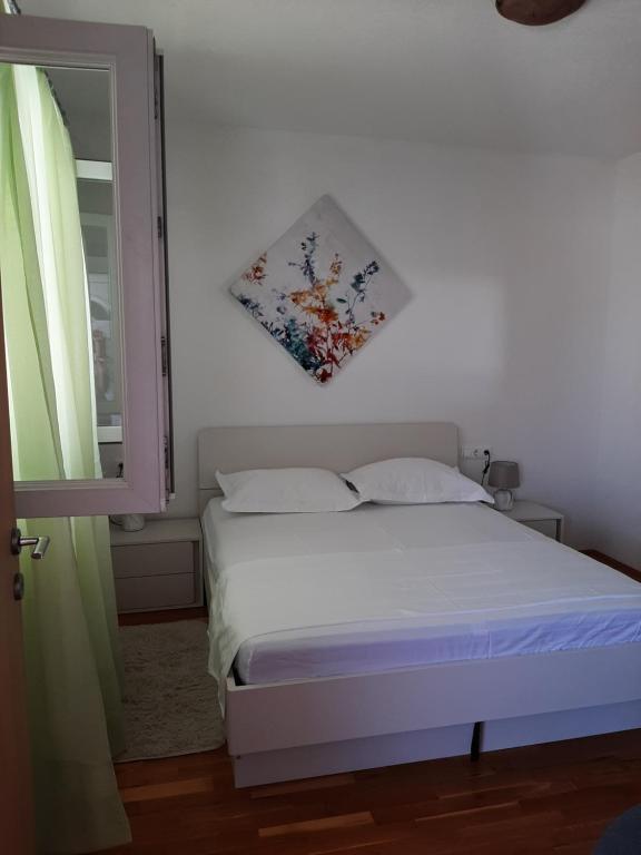 1 dormitorio con 1 cama y una ventana con una foto en la pared en Apartment Čiovo Radić, en Trogir