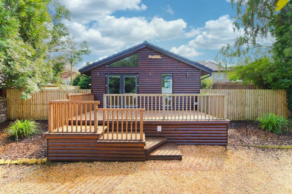 a small house with a deck with two benches at Braeside Cabin in Clackmannan