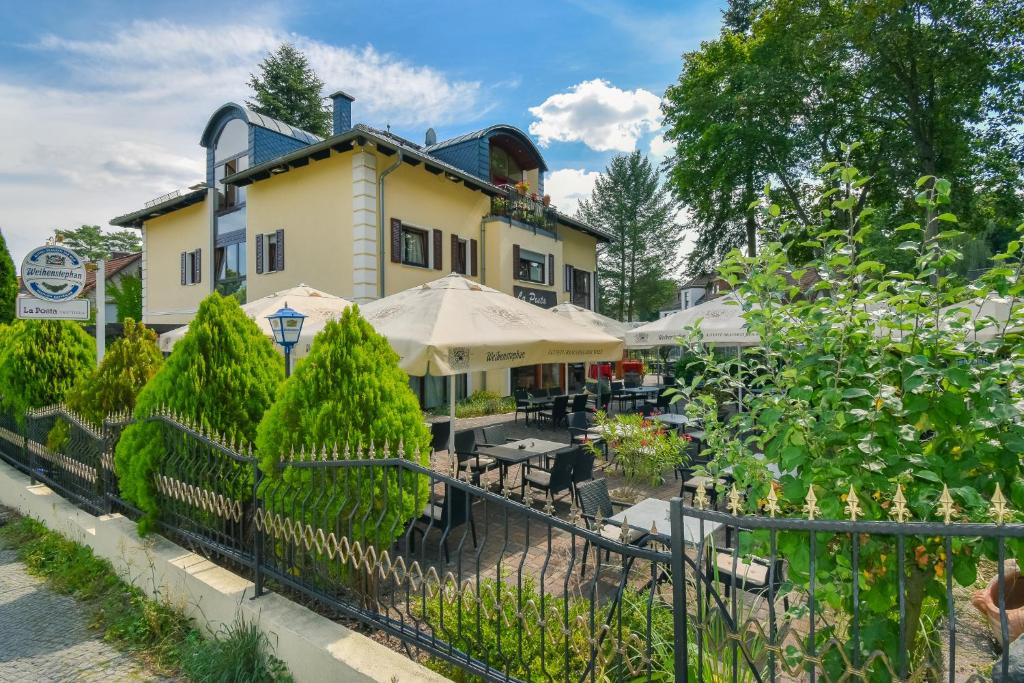 a building with tables and umbrellas in a garden at Boutique Hotel Sena in Berlin