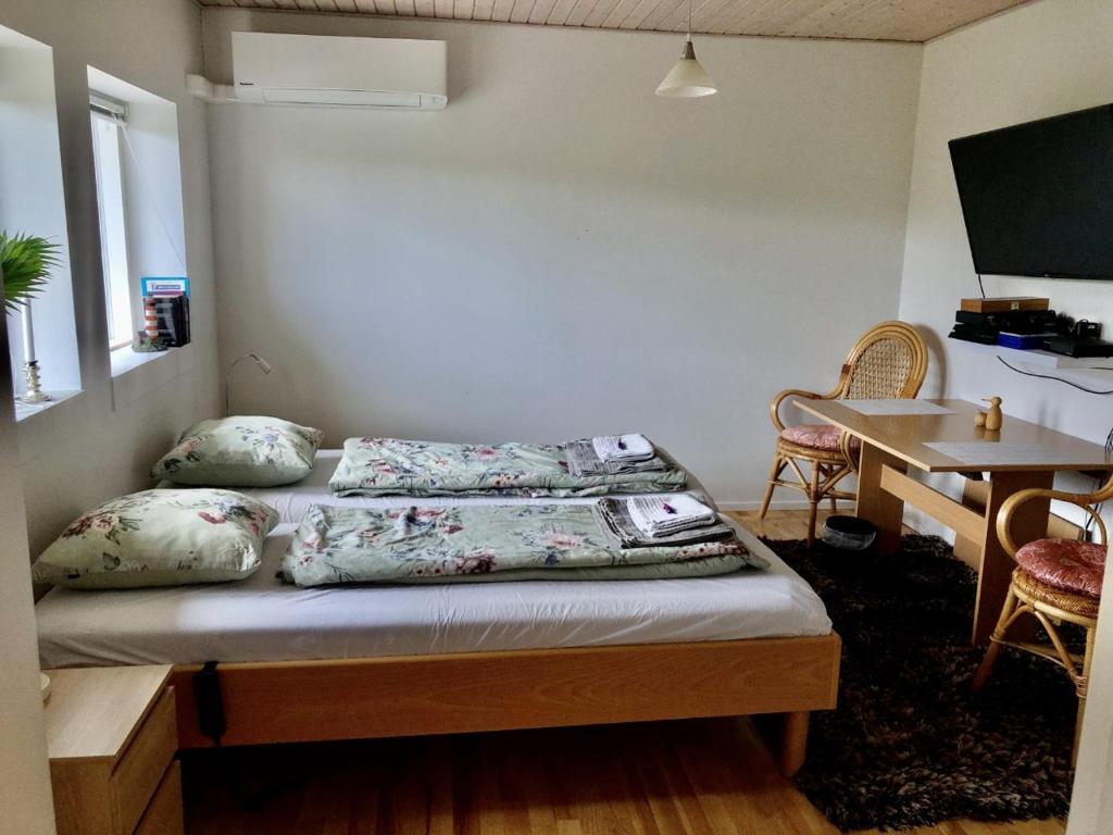 Falster værelse في Væggerløse: غرفة بسرير ومخدات وطاولة
