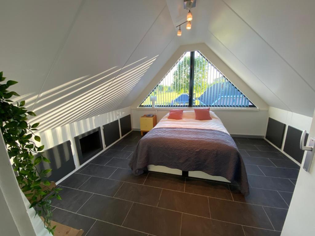 1 dormitorio en el ático con cama y ventana en De Wolbert en Wapenveld