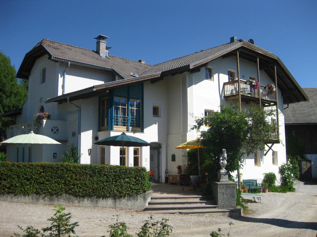 a large white house with people on a balcony at Pension Grünbacher in Falzes
